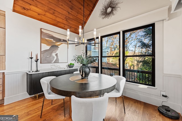 dining area featuring hardwood / wood-style flooring, plenty of natural light, lofted ceiling, and an inviting chandelier