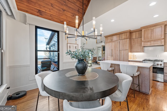 dining area featuring a chandelier, lofted ceiling, and light wood-type flooring