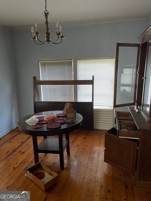 dining space with a chandelier, crown molding, and wood-type flooring