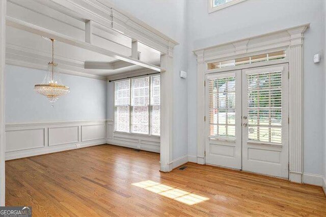 unfurnished dining area featuring hardwood / wood-style flooring, ornamental molding, a tray ceiling, and a notable chandelier