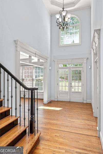 foyer entrance featuring a notable chandelier, hardwood / wood-style flooring, a wealth of natural light, and french doors