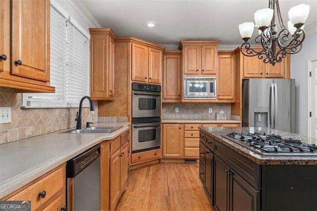 kitchen with ornamental molding, stainless steel appliances, decorative light fixtures, and a kitchen island