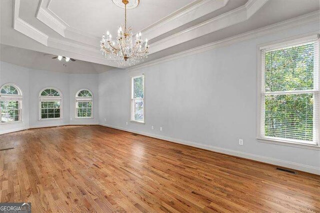 unfurnished bedroom featuring a raised ceiling, crown molding, hardwood / wood-style floors, and an inviting chandelier