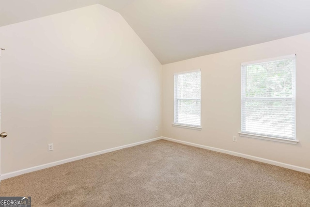 carpeted spare room with vaulted ceiling