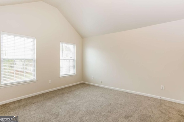 carpeted empty room with vaulted ceiling