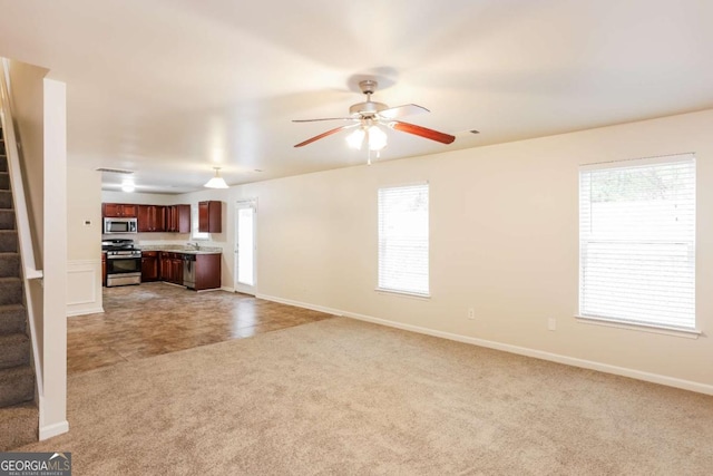 unfurnished living room featuring ceiling fan, sink, carpet floors, and a healthy amount of sunlight