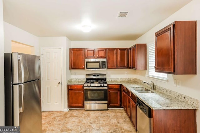 kitchen with light stone countertops, sink, and stainless steel appliances