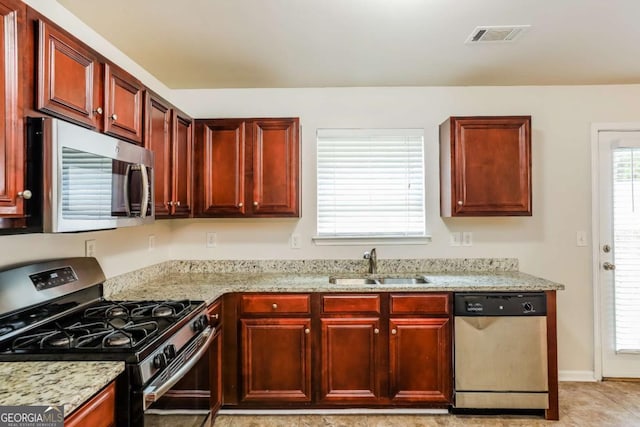 kitchen featuring light stone counters, sink, light tile patterned floors, and stainless steel appliances