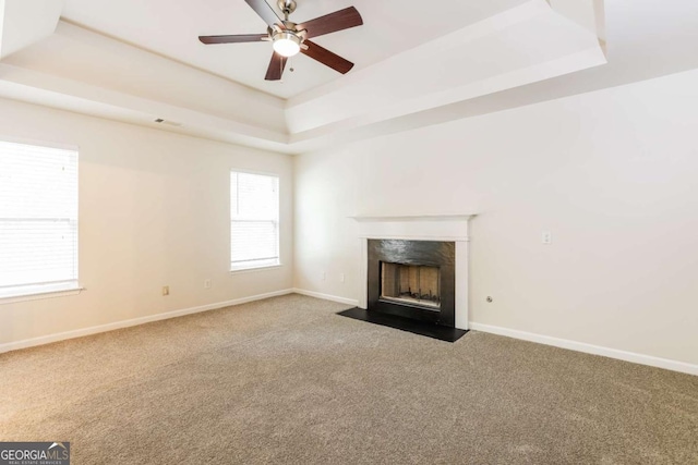 unfurnished living room featuring ceiling fan, carpet floors, and a tray ceiling