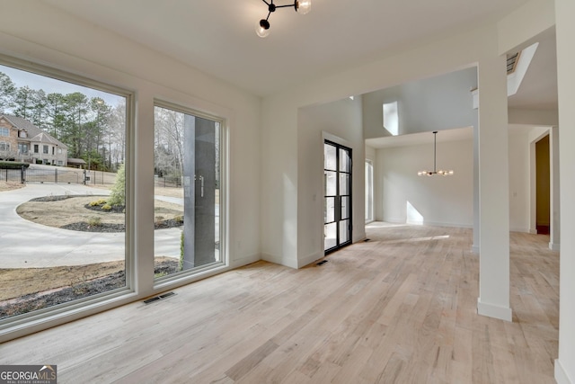 interior space featuring a healthy amount of sunlight, an inviting chandelier, and light hardwood / wood-style floors