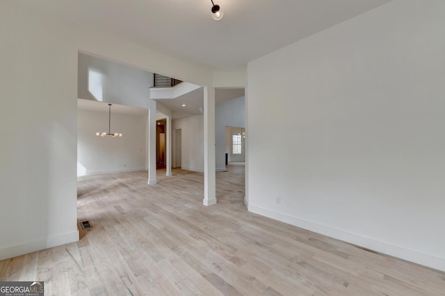 unfurnished room with a chandelier and light wood-type flooring