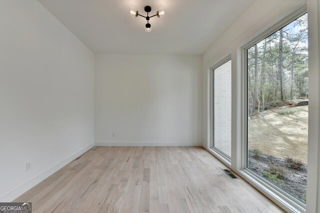 unfurnished dining area with an inviting chandelier and light hardwood / wood-style flooring