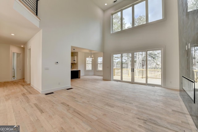 unfurnished living room with a notable chandelier and light wood-type flooring