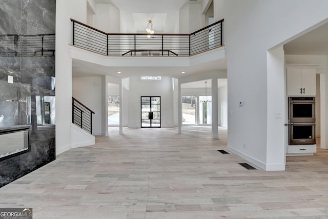 entryway featuring an inviting chandelier, a high ceiling, and light wood-type flooring