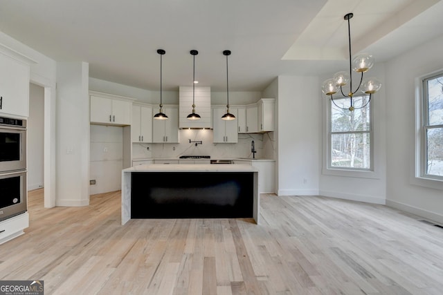 kitchen with a kitchen island, decorative light fixtures, white cabinetry, sink, and decorative backsplash