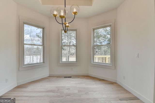 unfurnished dining area featuring a chandelier and light hardwood / wood-style floors