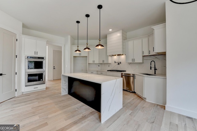 kitchen featuring sink, custom exhaust hood, white cabinetry, a center island, and appliances with stainless steel finishes