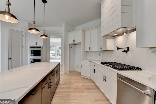 kitchen featuring pendant lighting, white cabinetry, backsplash, stainless steel appliances, and light stone countertops