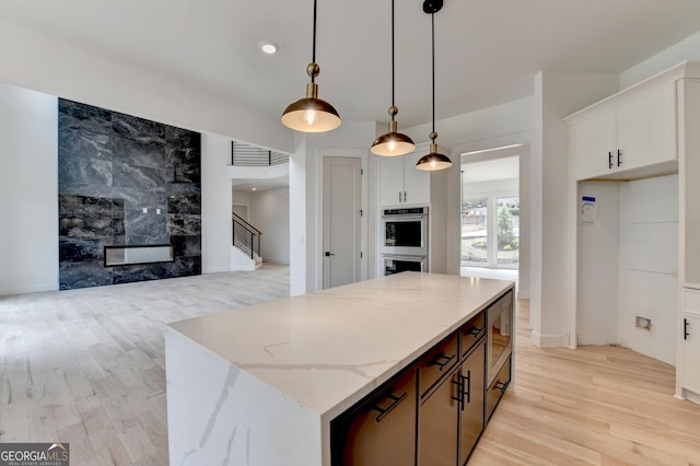 kitchen featuring a kitchen island, decorative light fixtures, white cabinets, stainless steel appliances, and light stone countertops