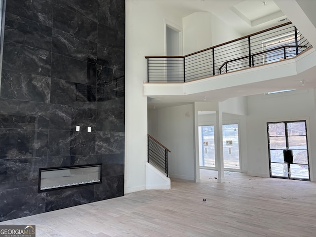 interior space with a tiled fireplace, hardwood / wood-style floors, tile walls, and a high ceiling