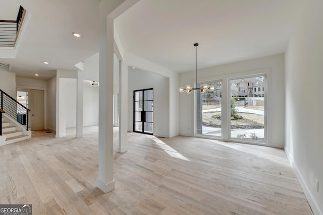 unfurnished dining area featuring a notable chandelier and light hardwood / wood-style flooring