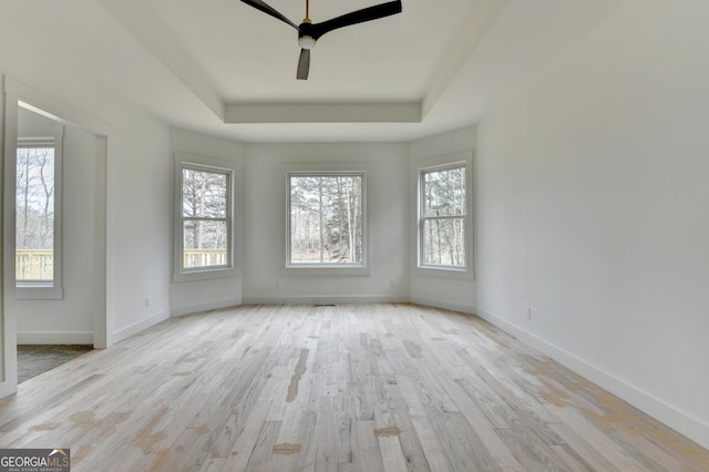 spare room featuring ceiling fan, a tray ceiling, and light hardwood / wood-style floors