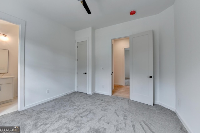 unfurnished bedroom featuring connected bathroom, light colored carpet, and ceiling fan