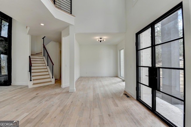 entryway with a towering ceiling and light wood-type flooring