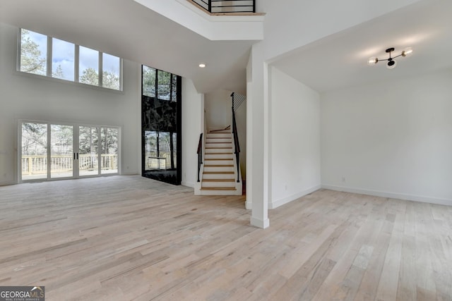 entrance foyer featuring a high ceiling, a high end fireplace, and light hardwood / wood-style floors