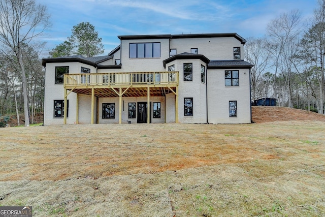 rear view of house featuring a wooden deck and a yard