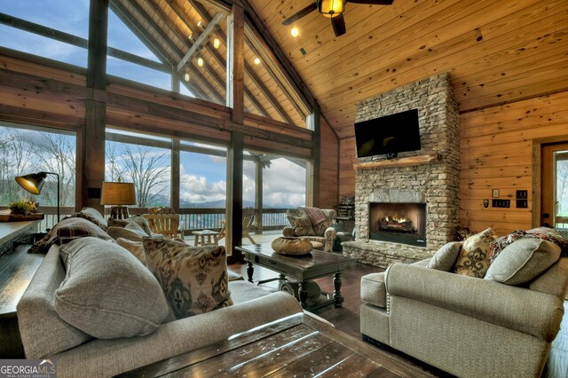 living room featuring high vaulted ceiling, a stone fireplace, a wealth of natural light, and ceiling fan