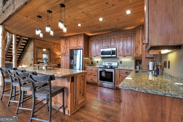 kitchen featuring pendant lighting, sink, dark hardwood / wood-style flooring, light stone counters, and stainless steel appliances