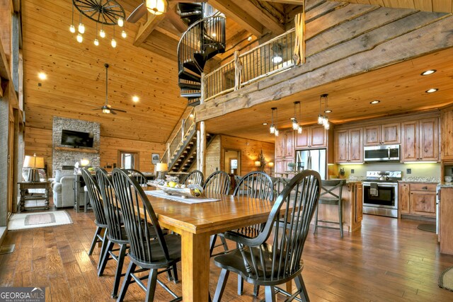 dining area featuring ceiling fan, dark hardwood / wood-style flooring, beamed ceiling, high vaulted ceiling, and wood walls