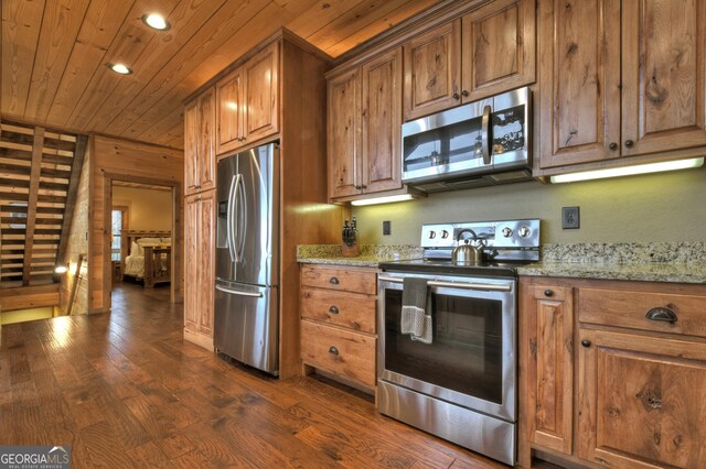 kitchen with light stone countertops, stainless steel appliances, dark wood-type flooring, and wooden ceiling