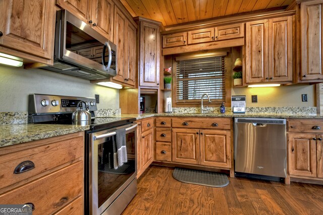 kitchen with light stone countertops, appliances with stainless steel finishes, dark hardwood / wood-style floors, and sink