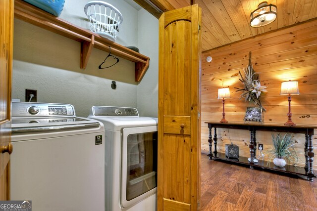 laundry room with wooden walls, washer and clothes dryer, wooden ceiling, and dark hardwood / wood-style floors