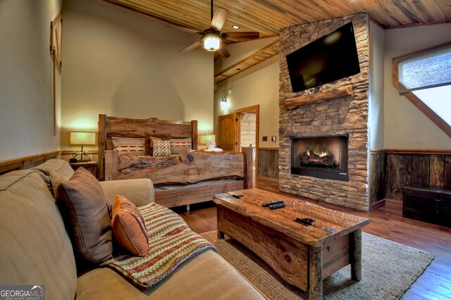 bedroom featuring ceiling fan, wooden ceiling, hardwood / wood-style floors, vaulted ceiling, and a fireplace