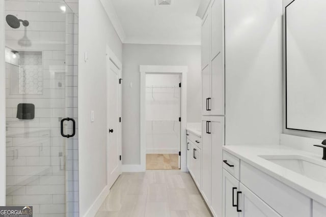 bathroom with a shower with door, vanity, and ornamental molding