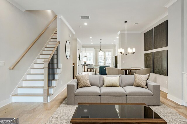 unfurnished living room featuring built in shelves, light wood-type flooring, an inviting chandelier, and sink