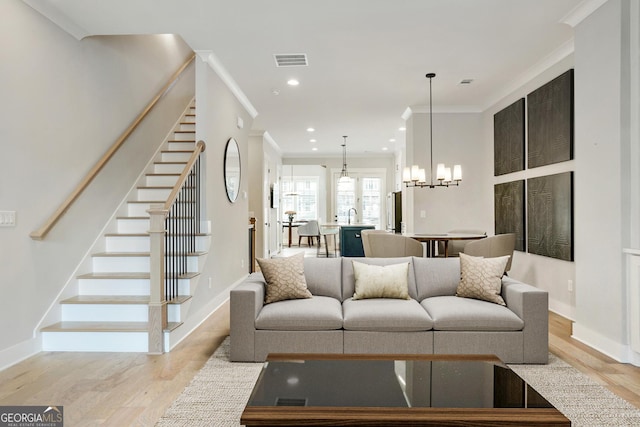 living area with light wood-style floors, stairs, visible vents, and ornamental molding