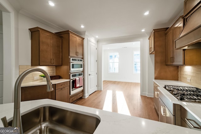 kitchen featuring light stone countertops, custom exhaust hood, tasteful backsplash, and sink