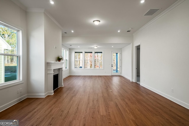 unfurnished living room featuring a wealth of natural light, ornamental molding, and hardwood / wood-style floors