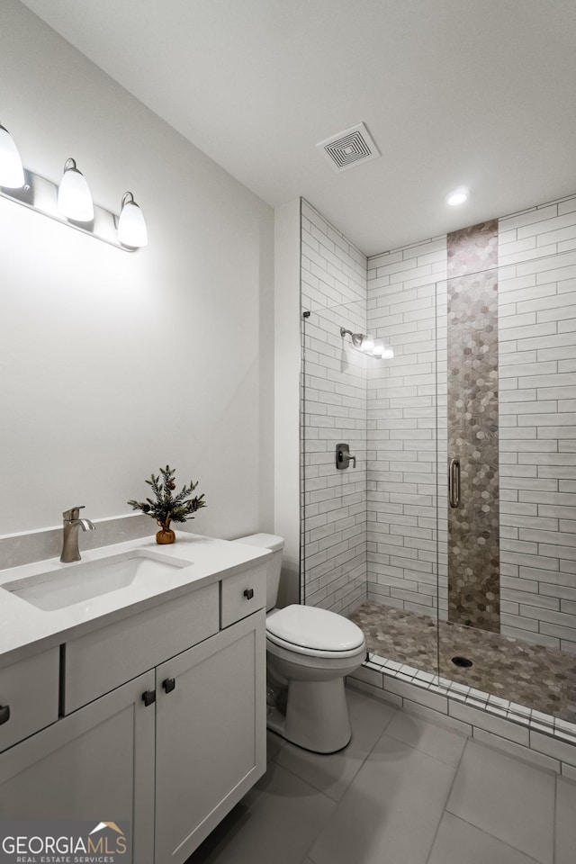 bathroom featuring tile patterned floors, a shower with door, toilet, and vanity