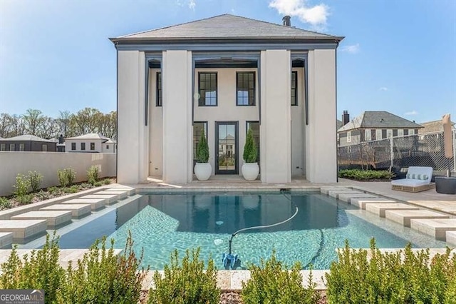 rear view of property with a fenced in pool and an outdoor structure