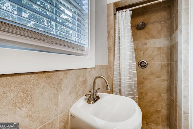 bathroom featuring a shower with curtain, sink, and tile walls