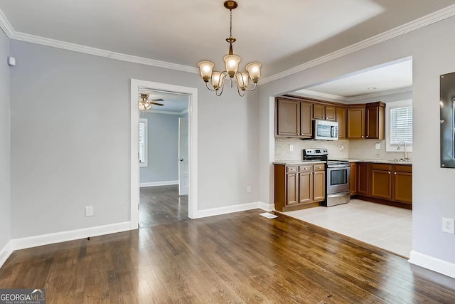 kitchen with sink, light hardwood / wood-style flooring, backsplash, decorative light fixtures, and appliances with stainless steel finishes