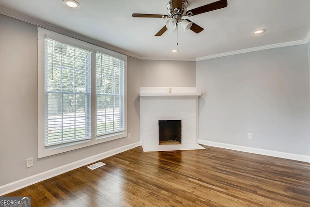 unfurnished living room featuring hardwood / wood-style floors, a healthy amount of sunlight, crown molding, and a fireplace