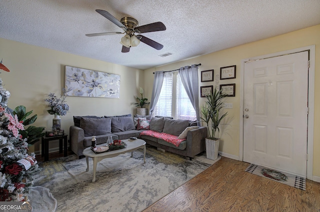 living room featuring ceiling fan, wood-type flooring, and a textured ceiling