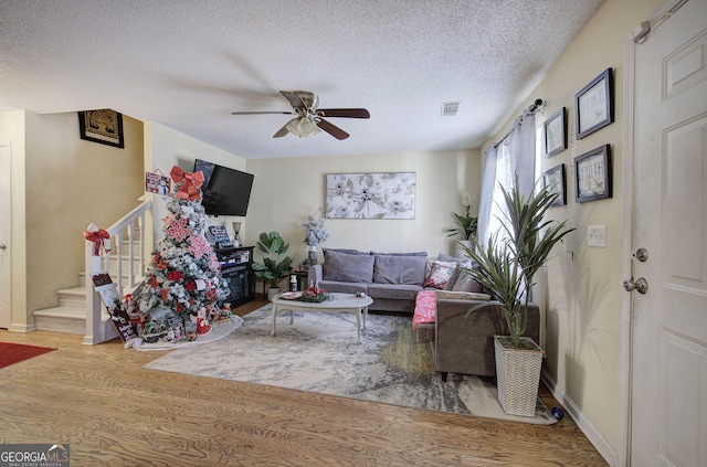 living room featuring hardwood / wood-style floors, a textured ceiling, and ceiling fan