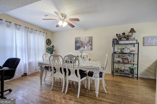 dining room with ceiling fan, a textured ceiling, and hardwood / wood-style flooring